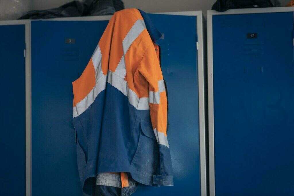 Veste de sécurité orange et bleu accrochée sur une porte de casier